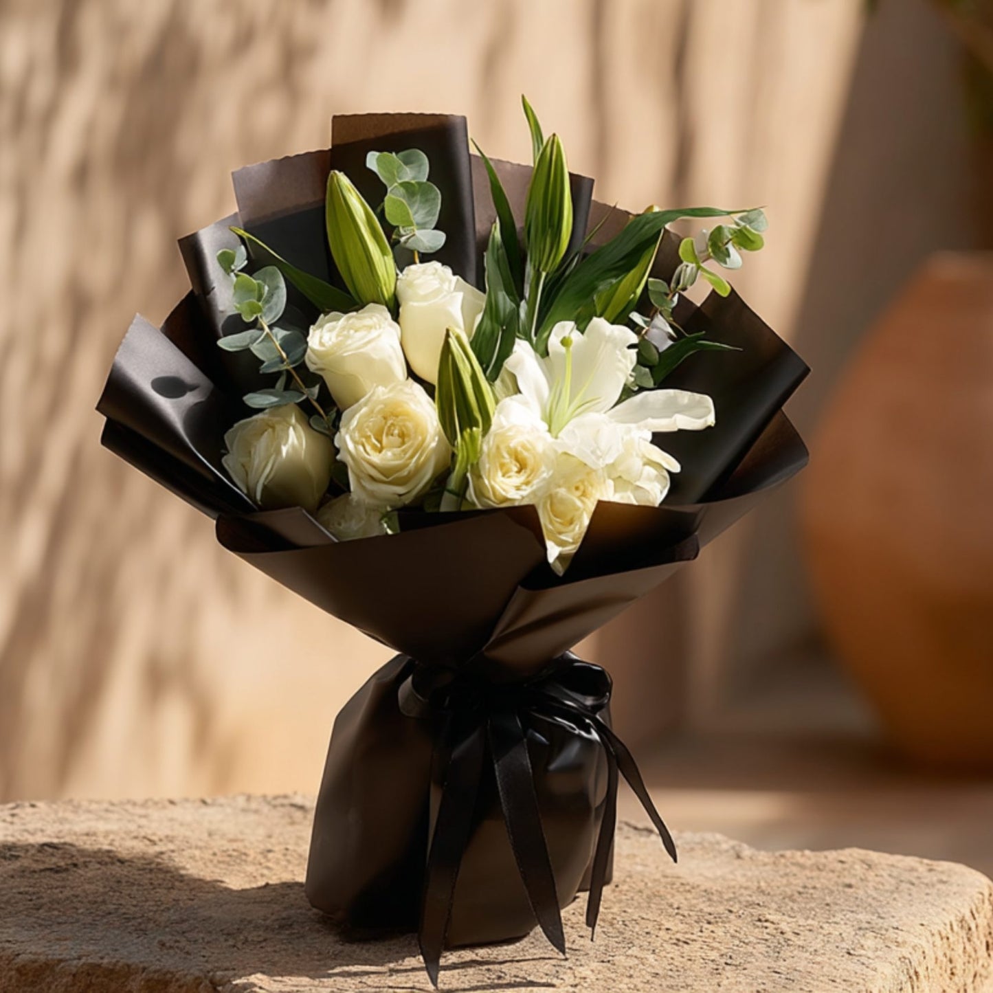 Hand-tied bouquet of roses with lilies and eucalyptus in elegant black wrapping by Aiwa Flowers Dubai
