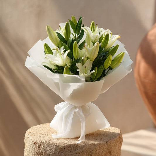 Hand-tied bouquet of 10 white lilies in elegant white wrapping, handcrafted by Aiwa Flowers in Dubai
