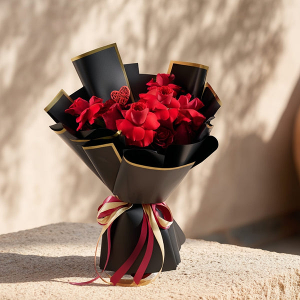Hand-tied bouquet of 15 red roses with heart ornaments in elegant black wrapping by Aiwa Flowers Dubai
