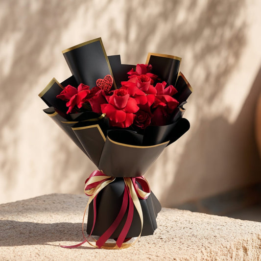 Hand-tied bouquet of 15 red roses with heart ornaments in elegant black wrapping by Aiwa Flowers Dubai
