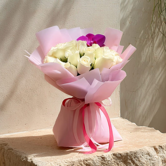 Hand-tied bouquet of 15 red roses with heart ornaments in elegant black wrapping by Aiwa Flowers Dubai
