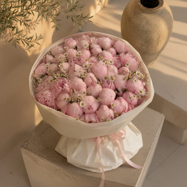 Romantic pink peony bouquet accented with chamomile-style daisies in soft white wrapping, luxury floral gift in Dubai.