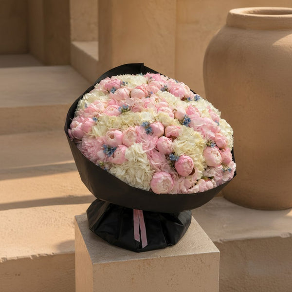 Luxury bouquet of pink peonies and white hydrangeas wrapped in premium black paper, sophisticated flower arrangement in Dubai.