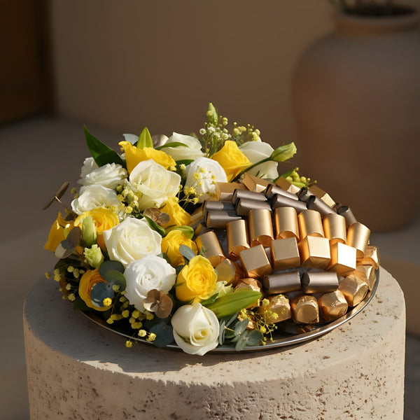 Rahmah floral tray arrangement with white and yellow roses, lisianthus, lilies, eucalyptus, gypsophila, and Patchi chocolates by Aiwa Flowers Dubai
