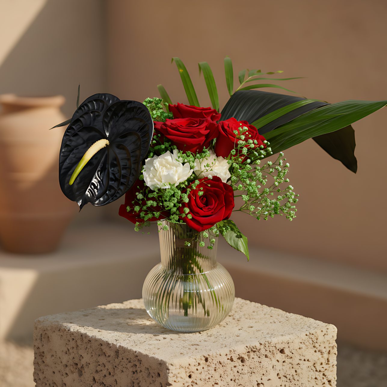 Ras Al Khaimah floral arrangement with red roses, white carnations, black anthurium, and greenery in a clear glass vase by Aiwa Flowers Dubai