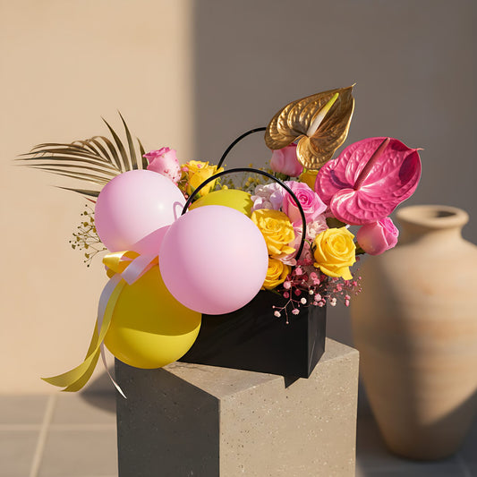 Sugar Cookie floral arrangement with pink and yellow balloons, roses, hydrangea, gypsophila, and anthuriums in a bag-box by Aiwa Flowers Dubai