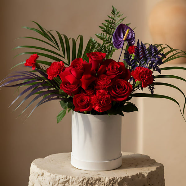 Tropical Fusion white velvet box arrangement with red roses, carnations, anthurium, and foliage by Aiwa Flowers Dubai