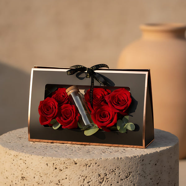 Tube Arrangement with red roses, eucalyptus, and glass money tube presented in a gift box by Aiwa Flowers Dubai