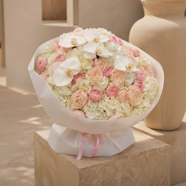 Elegant bouquet of white hydrangeas, white phalaenopsis orchids and blush garden roses in luxury wrapping, Dubai flower delivery.