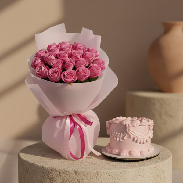 Pink rose bouquet wrapped in soft pink paper with ribbon beside a small pink celebration cake.