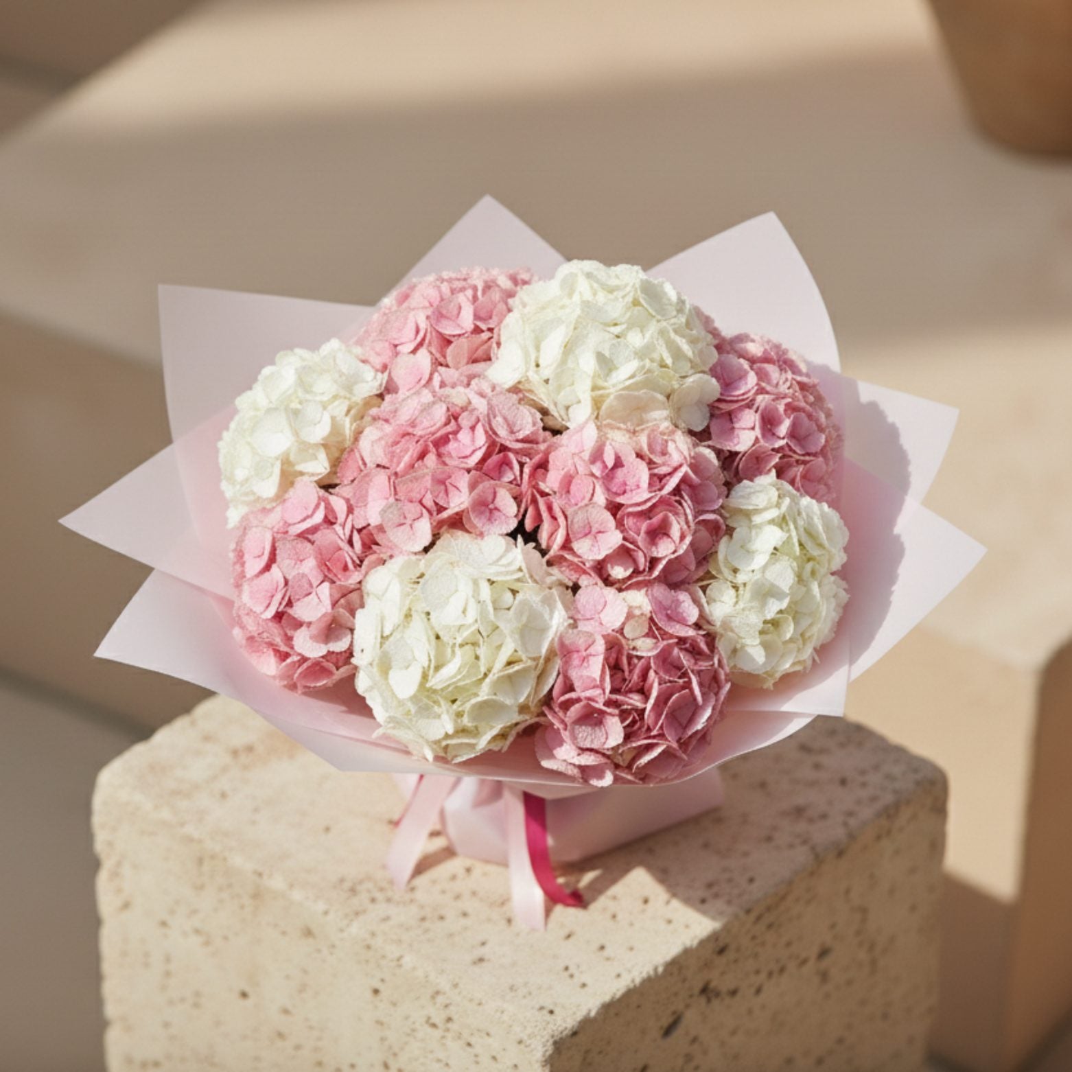 Top view of hydrangea bouquet with pink and white hydrangea blooms arranged in soft pink wrapping.