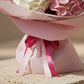 Close-up detail of pink bouquet wrapping and ribbon beneath pink and white hydrangea flowers.