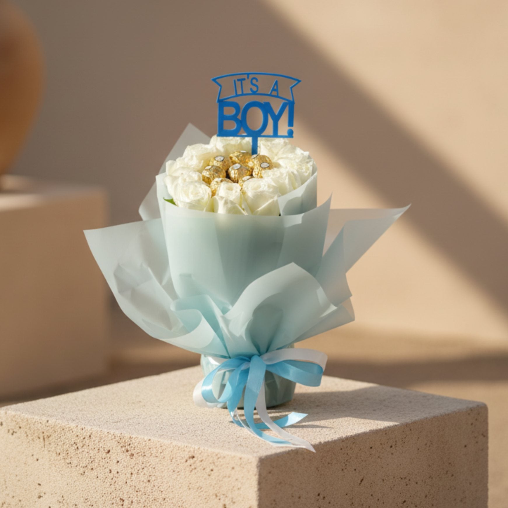It’s a Boy bouquet with white roses, Ferrero Rocher chocolates and baby boy topper in blue wrapping.
