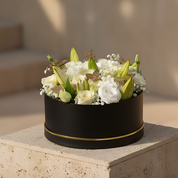 Black box floral arrangement with white roses, white carnations, white lilies, lisianthus, and soft white accents