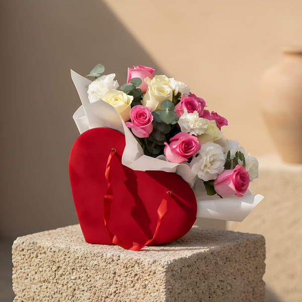 Red heart-shaped velvet box arrangement with white and pink roses, carnations, lisianthus, and eucalyptus