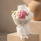 Pink hydrangea bouquet with white roses and orchid wrapped in elegant white paper with ribbon.