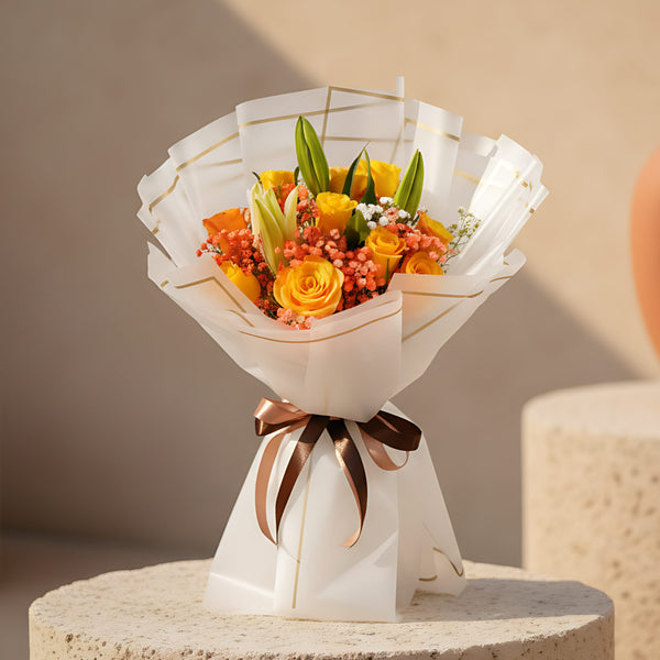 Hand-tied bouquet of yellow and orange roses with lily and gypsophila wrapped in trendy paper