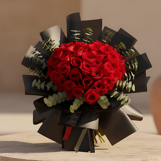 Heart-shaped hand-tied bouquet of red roses wrapped in elegant black paper