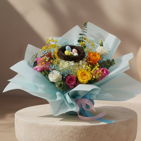 Pastel Garden bouquet with colorful roses, hydrangea, baby’s breath and decorative bird nest in sky blue wrapping.