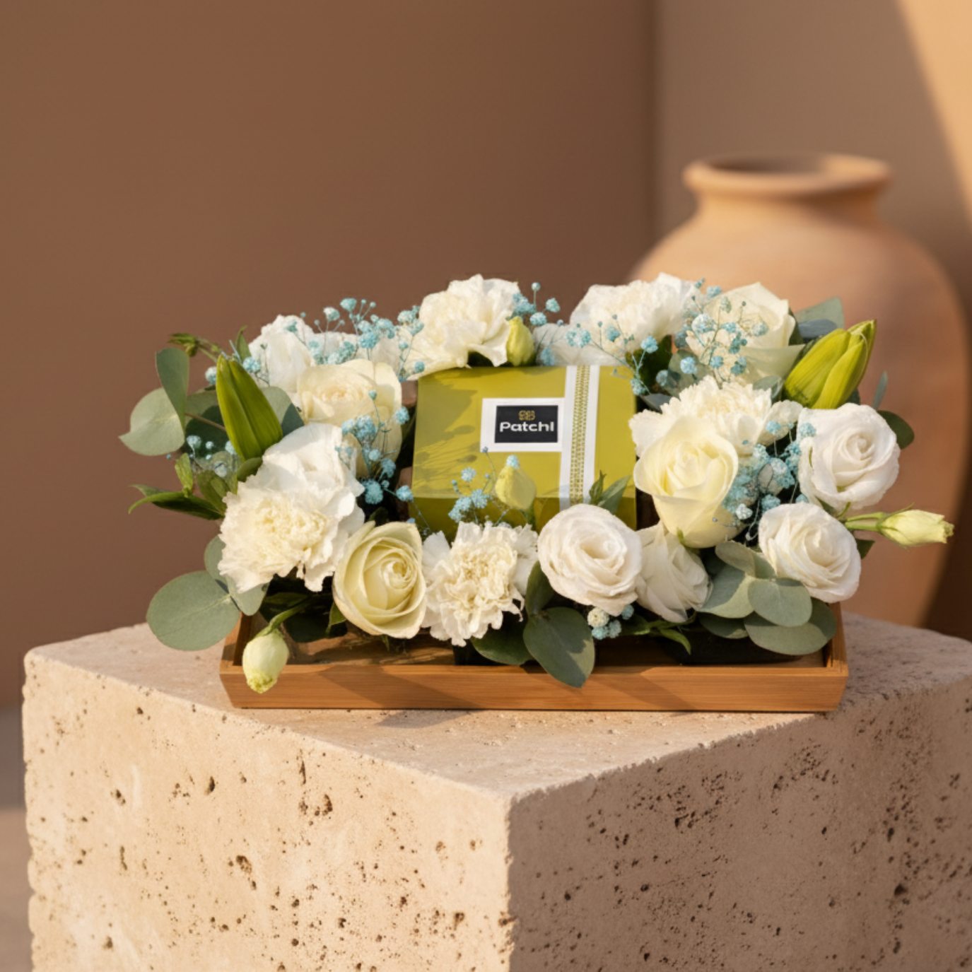 Patchi chocolate platter with white roses, carnations, lisianthus and blue gypsophila arranged on a tray.