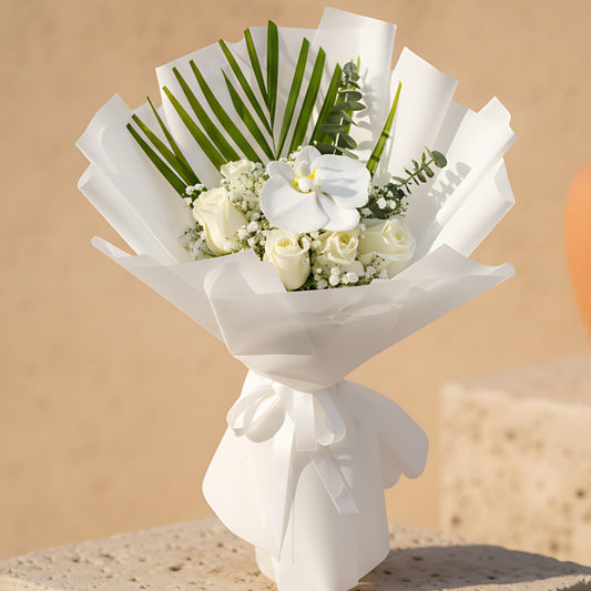 Hand-tied bouquet of white roses with a white orchid, gypsophila, and eucalyptus wrapped in elegant white paper