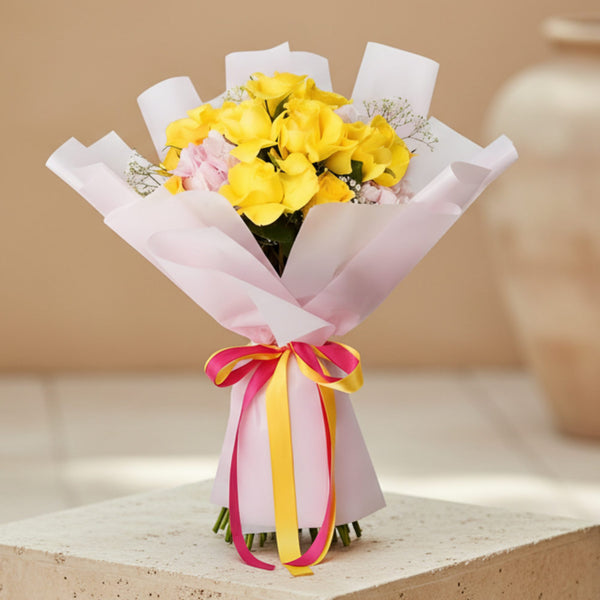 Hand-tied bouquet of yellow roses with pink hydrangea and gypsophila wrapped in pink paper