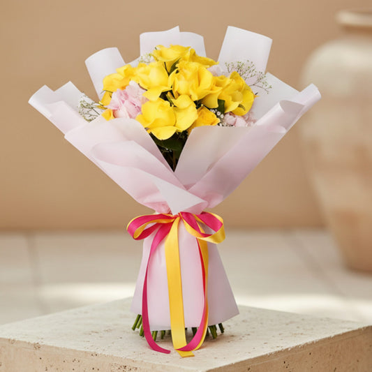 Hand-tied bouquet of yellow roses with pink hydrangea and gypsophila wrapped in pink paper
