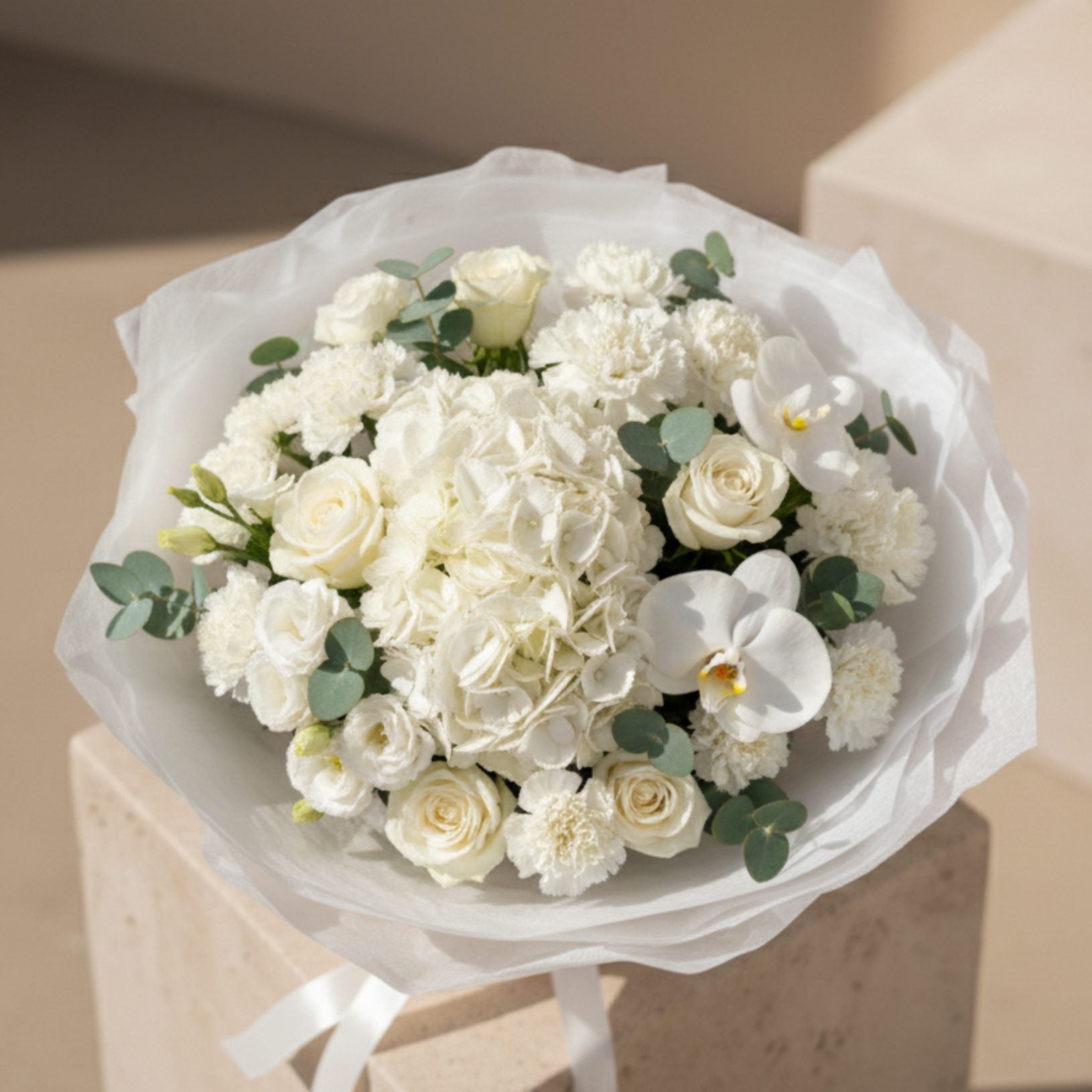 Top view of Pure Intention bouquet with white hydrangea, roses, orchid, and delicate white flowers.