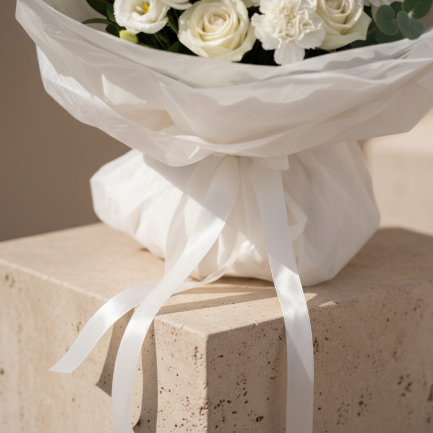 Close-up detail of white bouquet wrapping and ribbon on Pure Intention flower arrangement.
