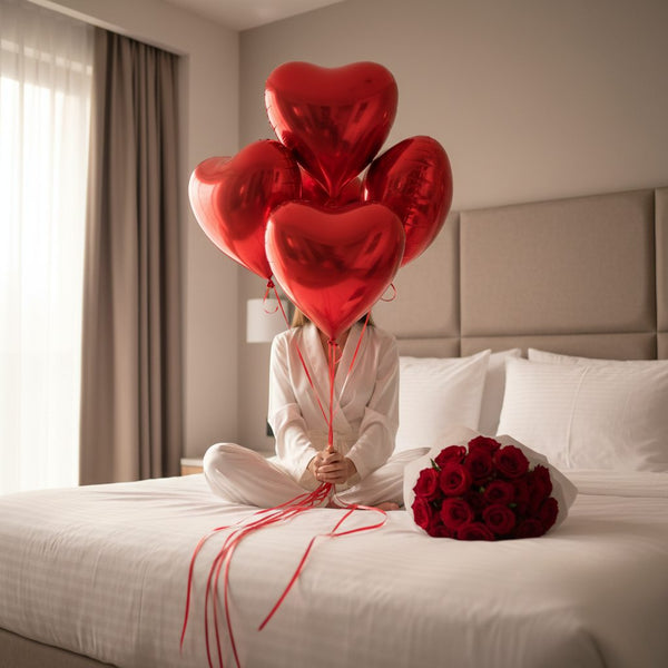 five red heart shaped helium balloons with 25 red roses bouquet on bed luxury romantic gift Dubai