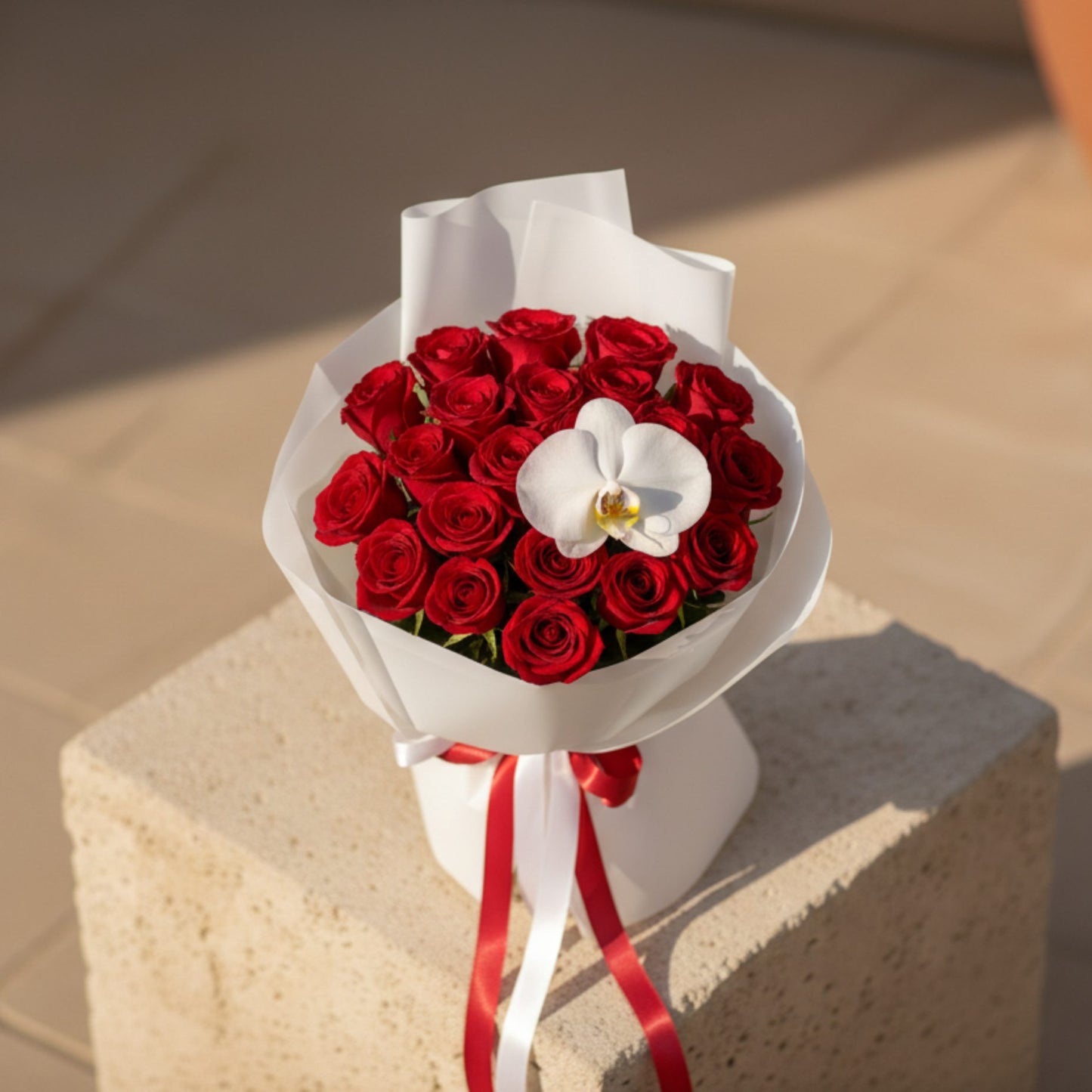 Top view of luxury red rose bouquet with white orchid centerpiece and satin ribbon.