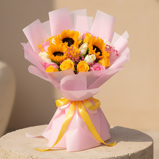 Hand-tied bouquet with sunflowers, pink, yellow and white roses, and gypsophila wrapped in pink paper