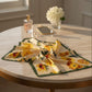 Sunflower print silk scarf displayed on table with perfume, mirror and pearl accessories.