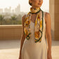 Woman wearing sunflower silk scarf with elegant dress and Dubai skyline background.