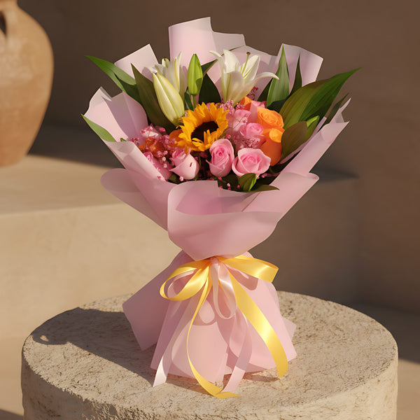 Hand-tied bouquet with sunflower, lilies, pink and orange roses, and gypsophila wrapped in pink paper