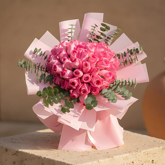 Heart-shaped hand-tied bouquet of pink roses wrapped in soft pink paper