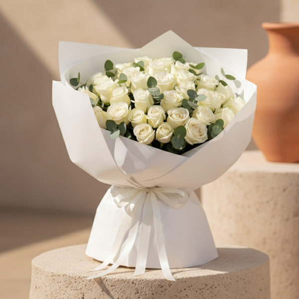 White rose bouquet with eucalyptus wrapped in elegant white paper and ribbon.