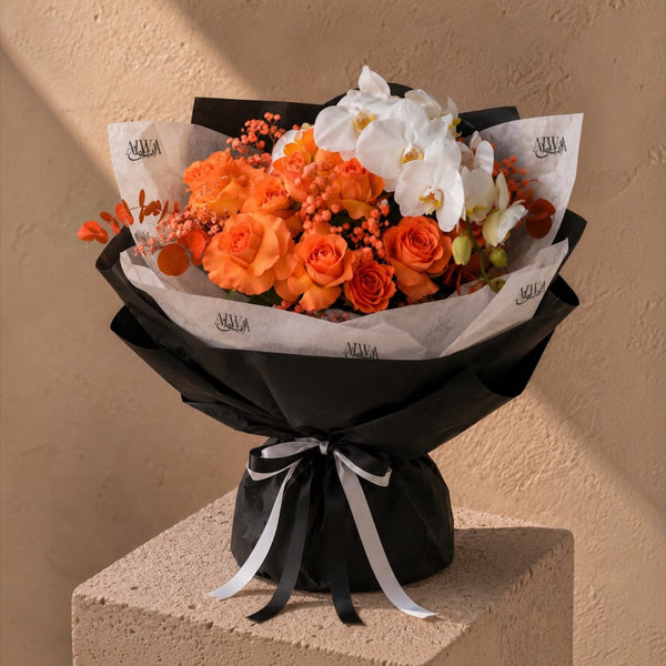 Orange rose and white orchid bouquet in black wrap by AIWA Flowers Dubai