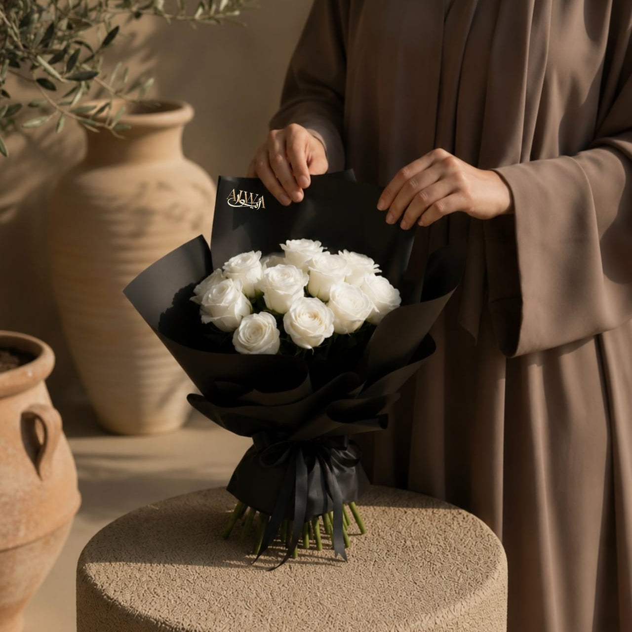 Woman holding a white rose bouquet in black wrap by AIWA Flowers Dubai