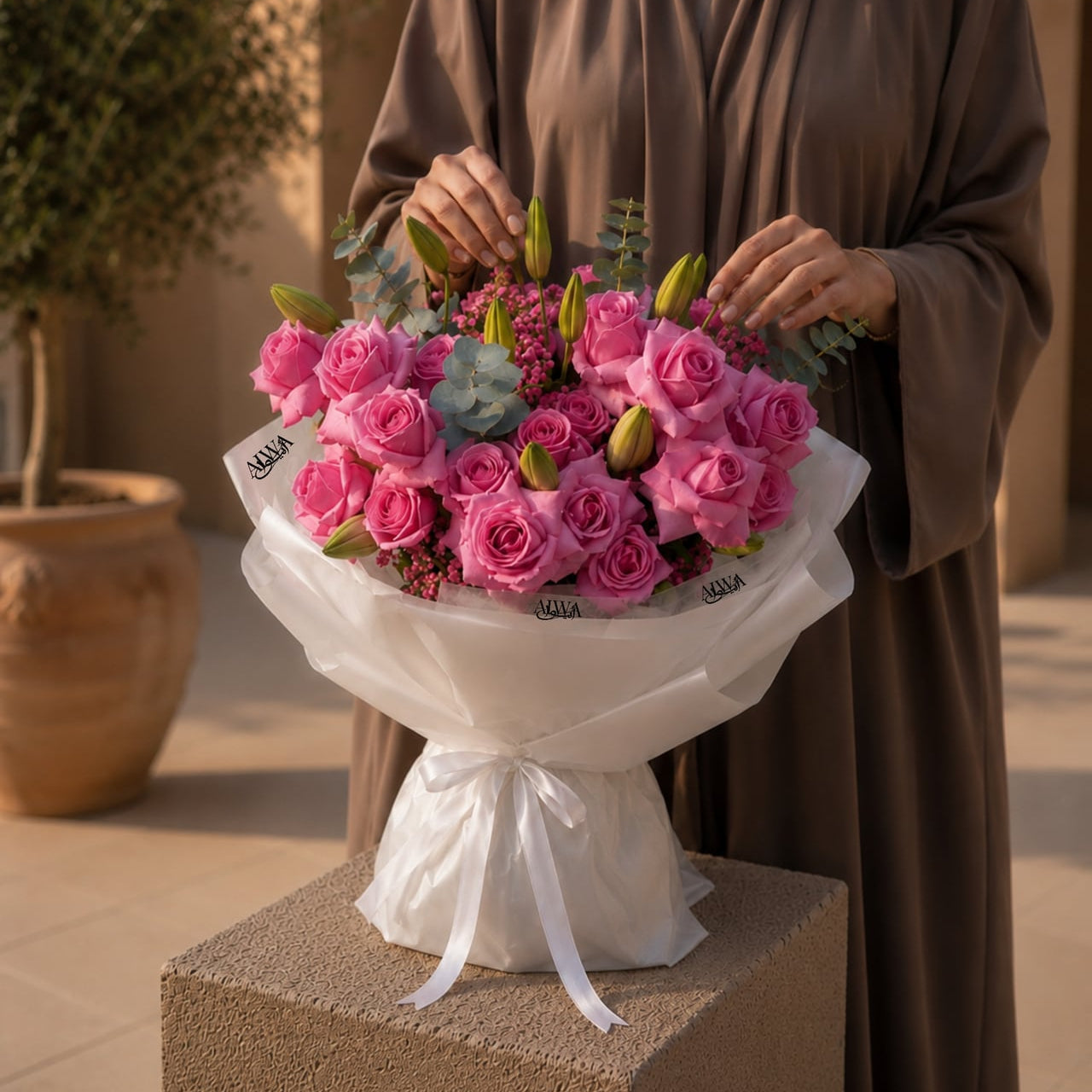 Woman holding a pink rose and lily bud bouquet by AIWA Flowers Dubai