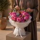 Woman holding a pink rose and lily bud bouquet by AIWA Flowers Dubai