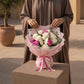 Woman holding a white and pink rose bouquet with butterfly accent by AIWA Flowers Dubai