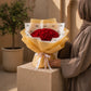 Woman holding a red rose bouquet in gold wrapping by AIWA Flowers Dubai