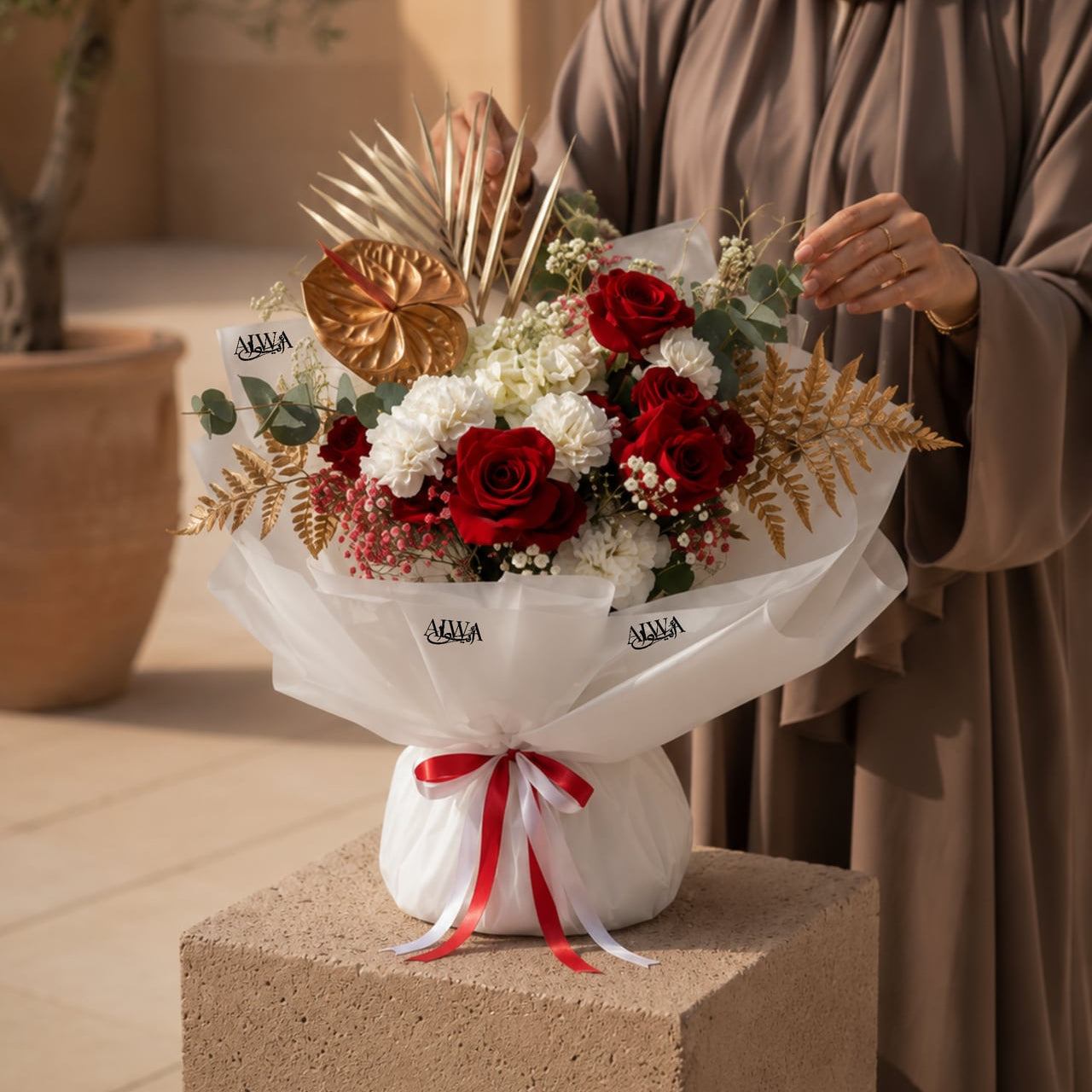 Woman holding a red rose bouquet with gold accents by AIWA Flowers Dubai
