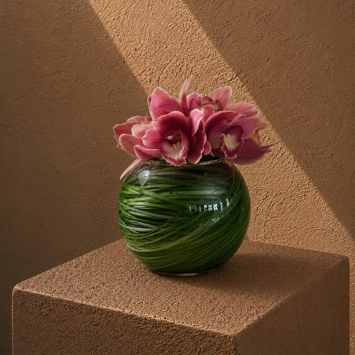 Contemporary pink cymbidium orchid arrangement in a round leaf-lined vase by AIWA Flowers