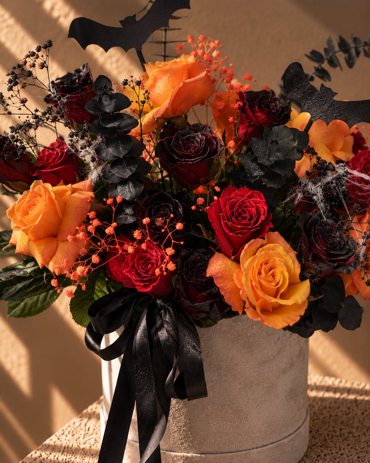 Close-up of orange and black roses, gypsophila and spider-web detail in the Creeper Halloween box