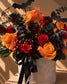 Close-up of orange and black roses, gypsophila and spider-web detail in the Creeper Halloween box