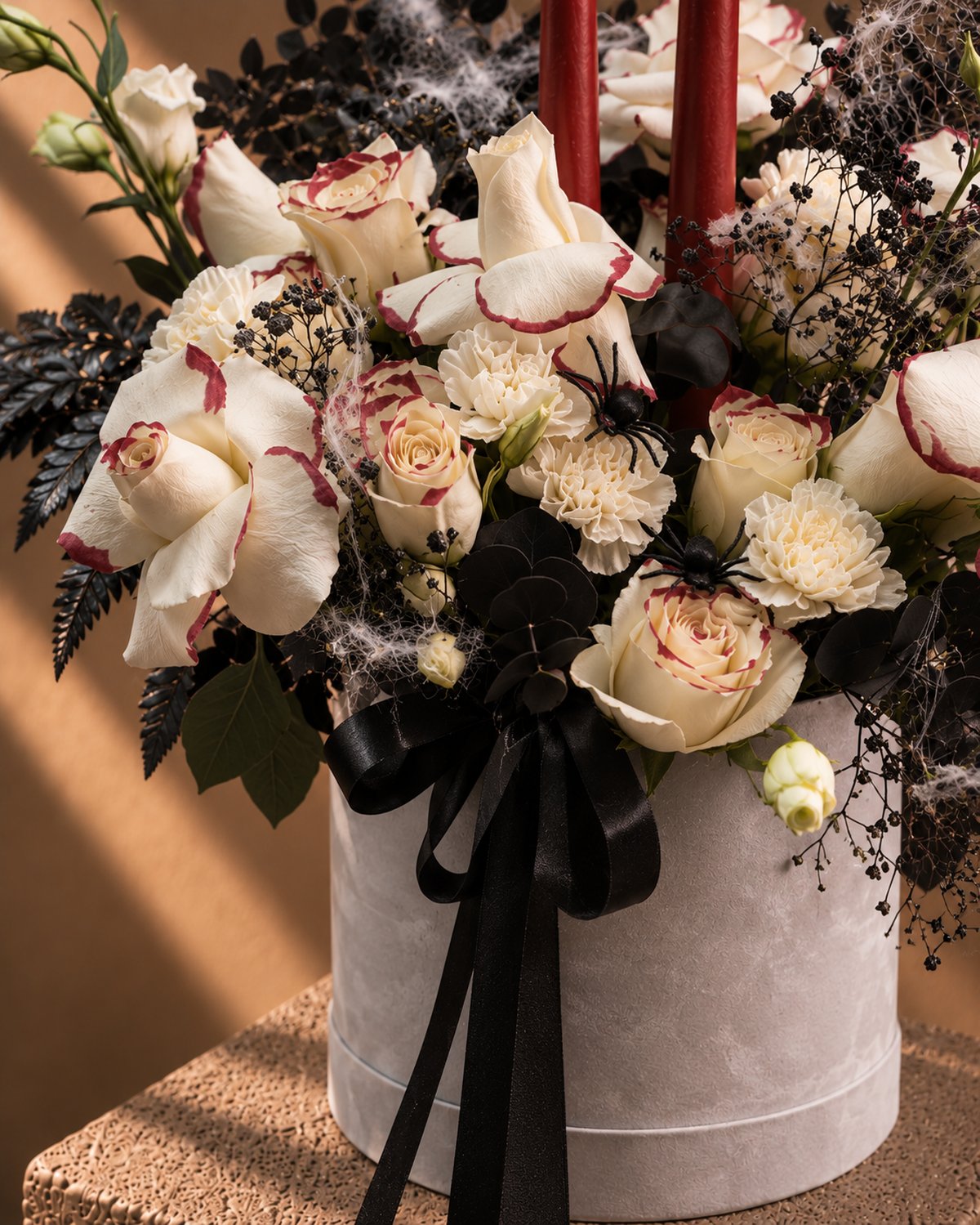 Close-up of red-edged white roses, white carnations and black fern in the Dagger Halloween box