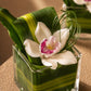 White cymbidium orchid with a folded green leaf in a clear glass cube - Eleanor by AIWA Flowers
