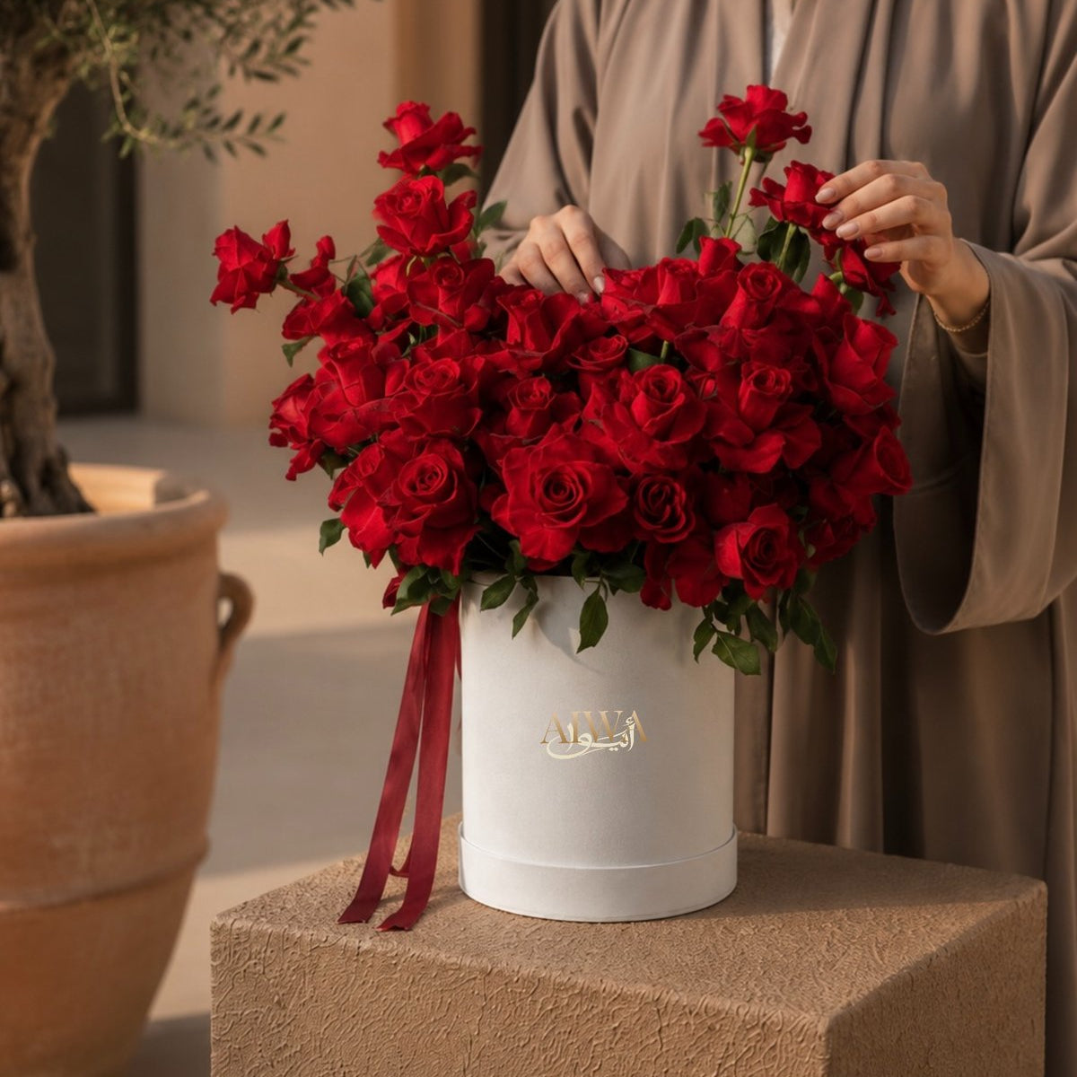 Woman holding a red roses box bouquet by AIWA Flowers Dubai